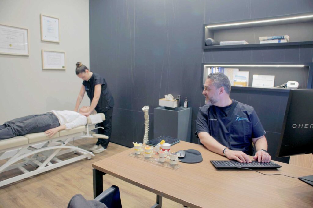 Quiropráctica realizando un ajuste a una cliente mientras otro profesional supervisa la consulta en Almería Quiropráctica