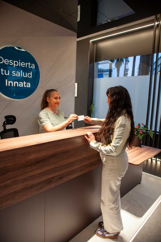 Recepcionista atendiendo a una clienta en la recepción de Almería Quiropráctica